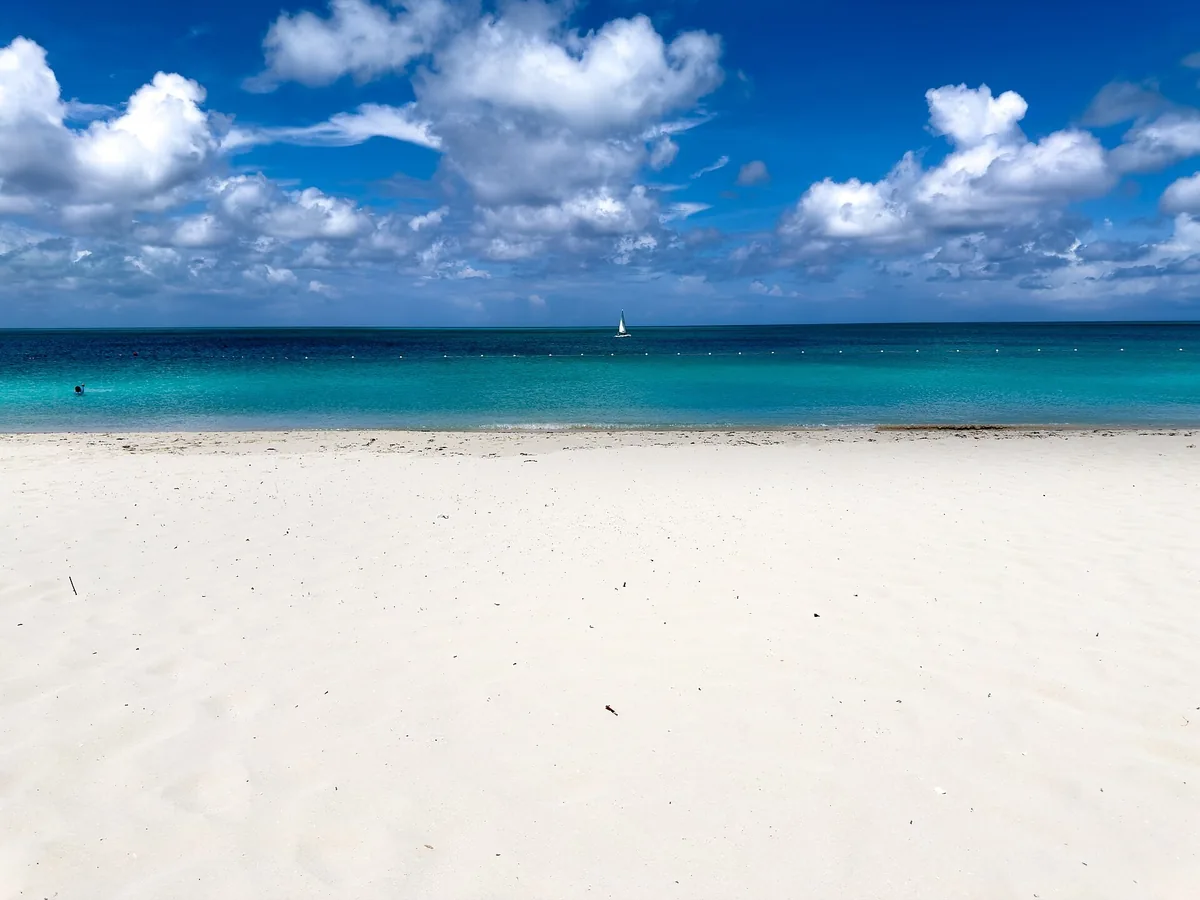 Wide white sand beach and bright turquoise sea under puffy clouds on Providenciales