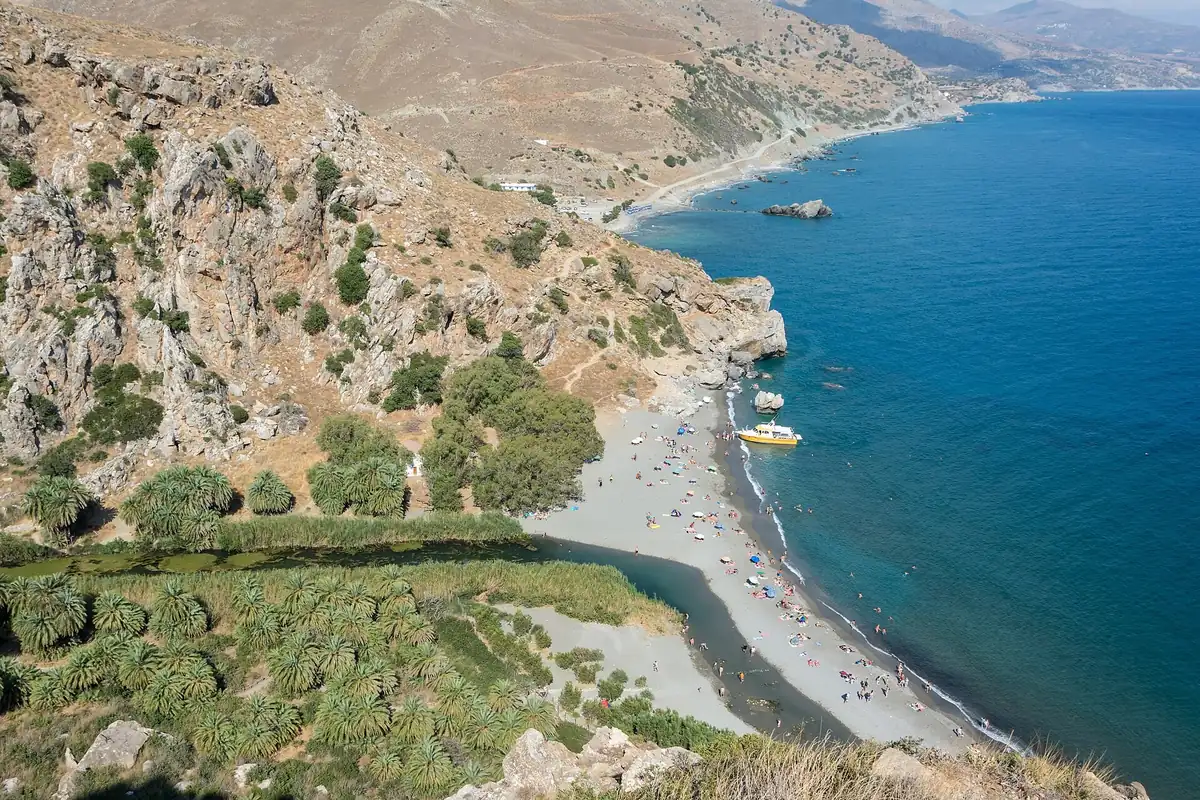 Preveli Beach on Crete seen from the cliffs, where a palm-lined river lagoon meets the Libyan Sea