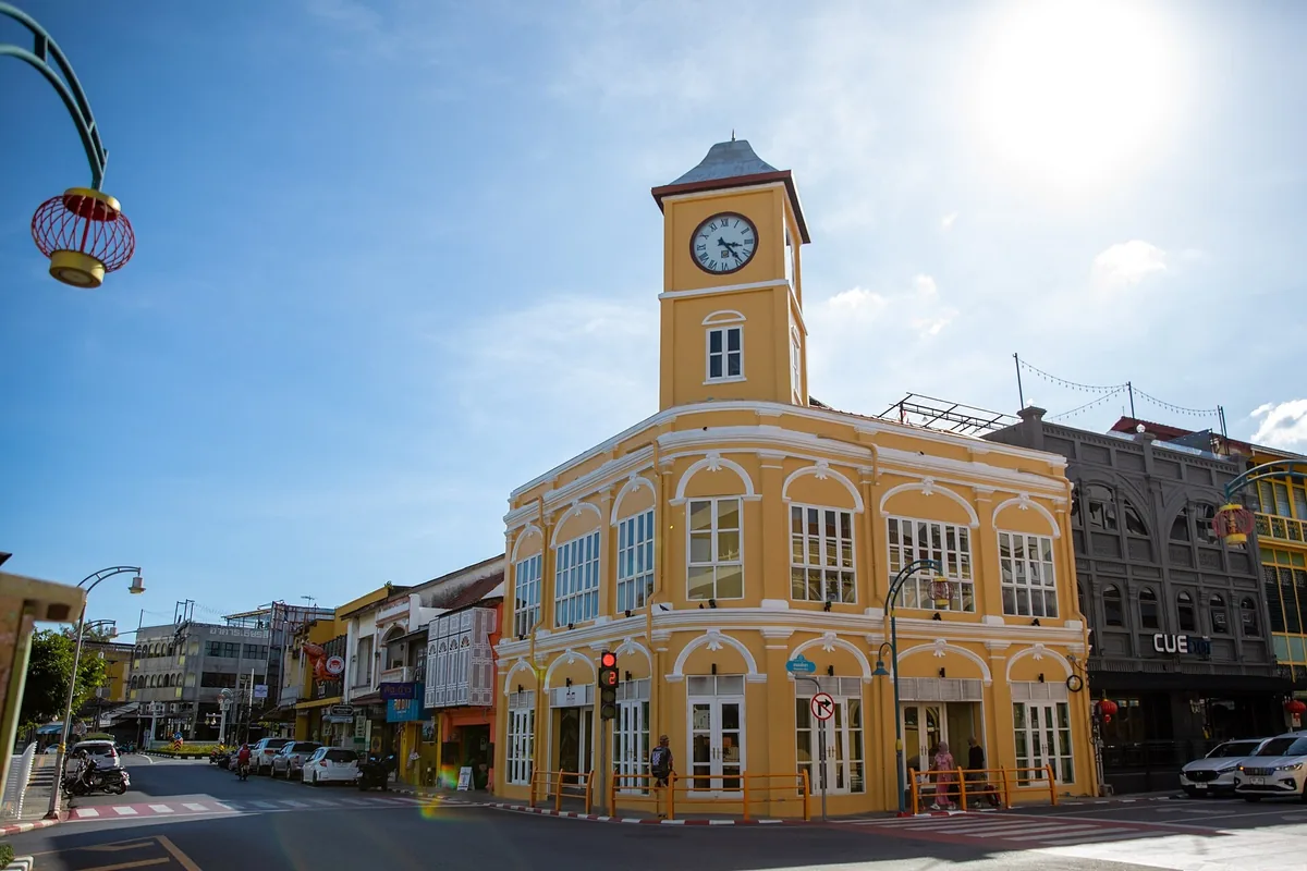 The yellow colonial-era former police station with its clock tower on a street corner in Phuket Old Town