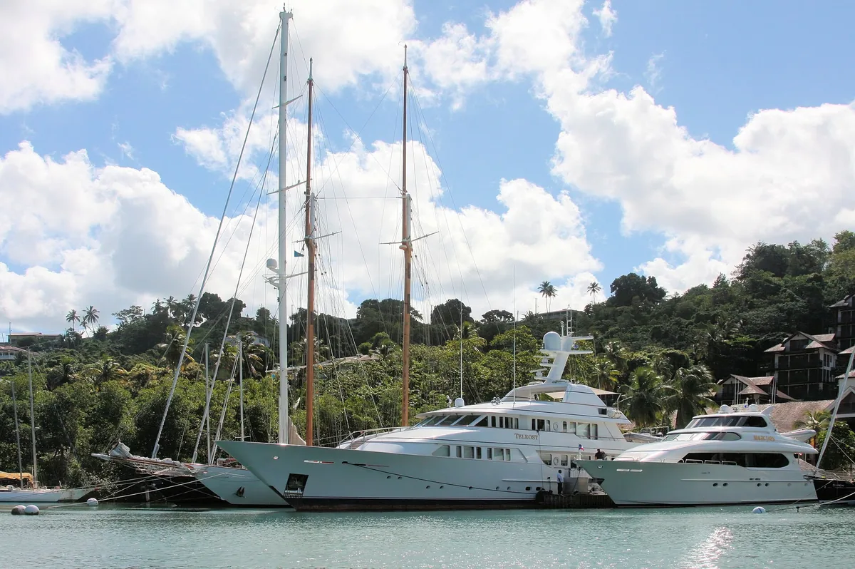 Tall-masted sailing yachts and motor yachts moored in Marigot Bay, Saint Lucia, against green hills