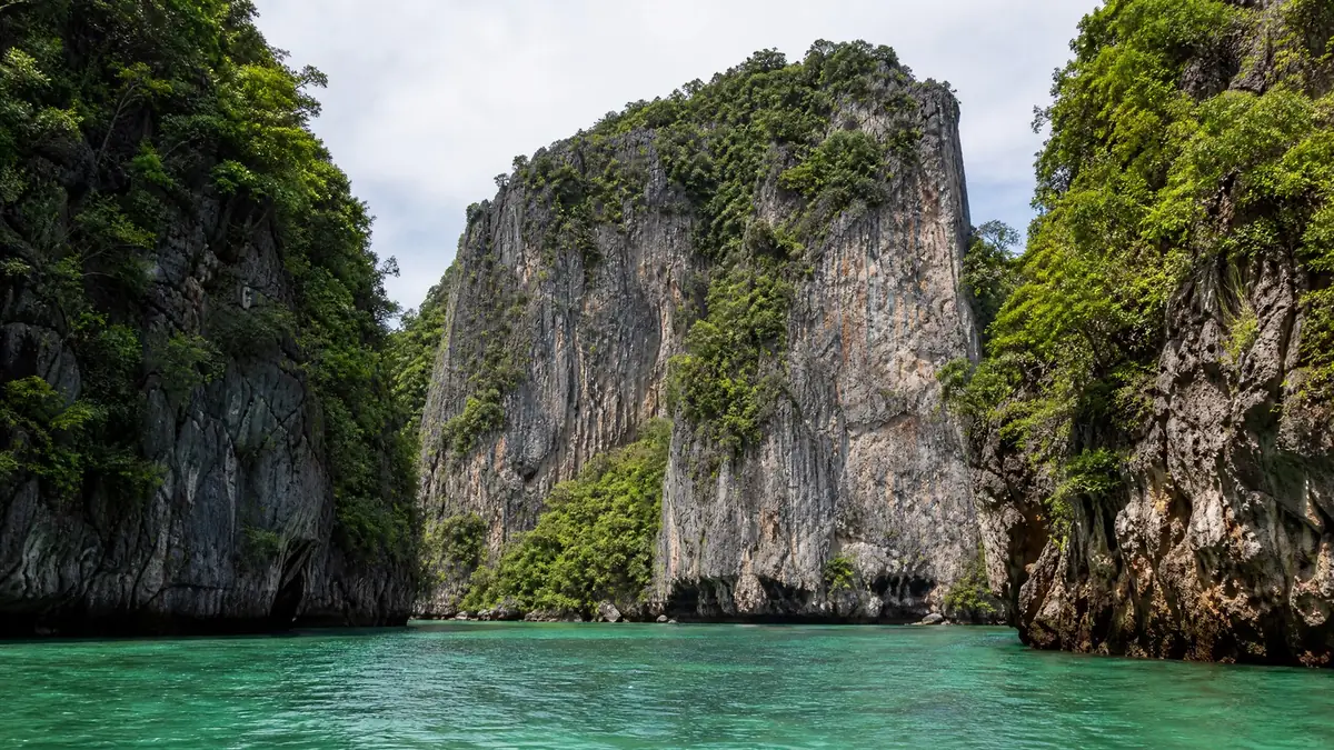 Steep jungle-topped limestone rocks rising from emerald water