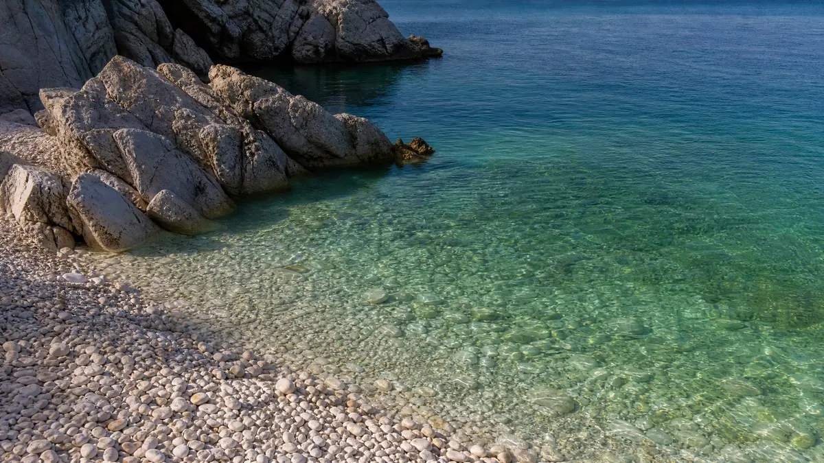 A small pebble cove with smooth white stones and clear green-blue water