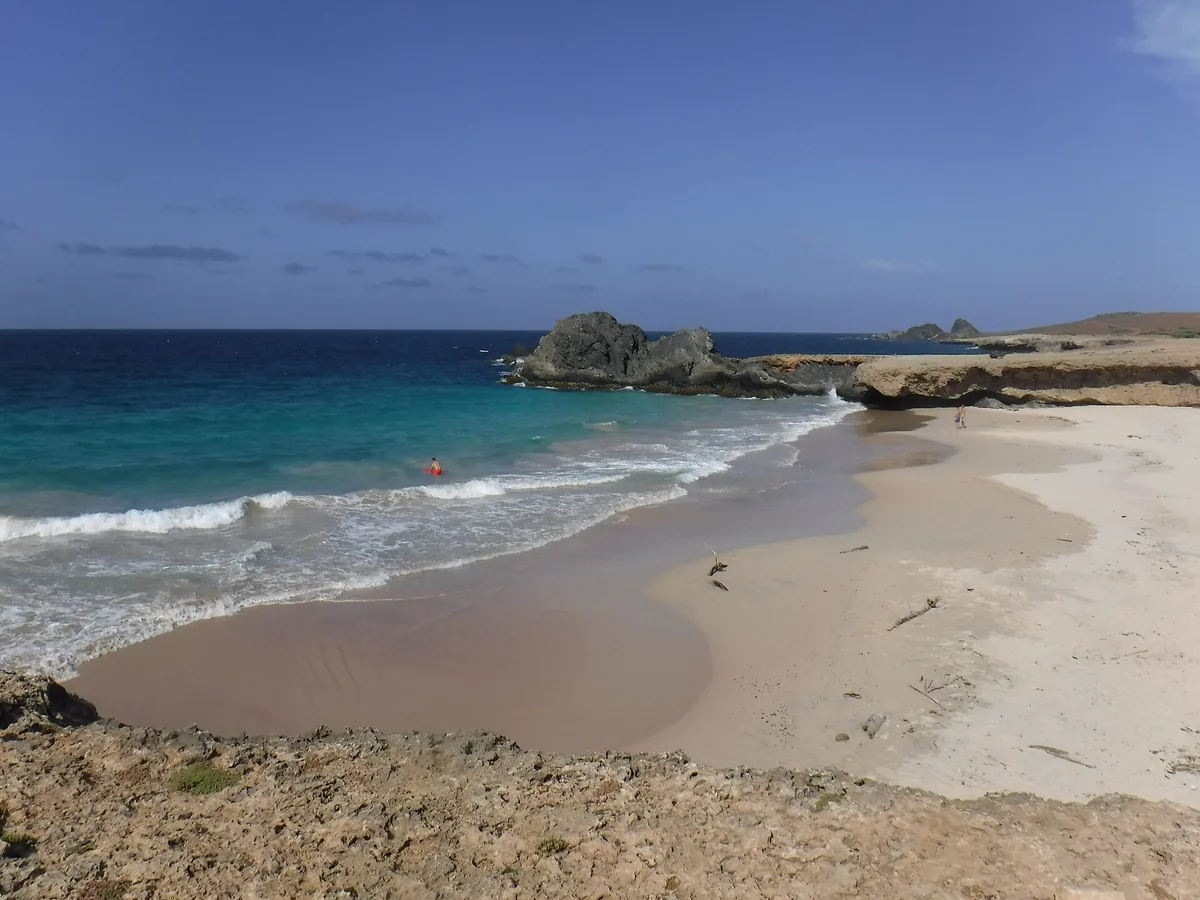 Waves rolling onto the pale sand of Andicuri Beach, a cove on the rugged north coast of Aruba