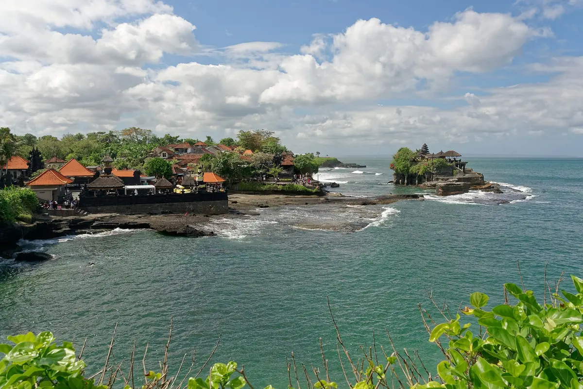 Tanah Lot temple on its rock islet off Bali's southwest coast, with waves washing over the reef