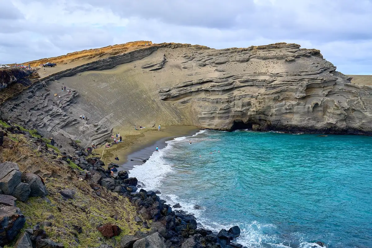 Turquoise surf in the cove below the eroded olive-green cliffs of Papakōlea Green Sand Beach on Hawaii Island