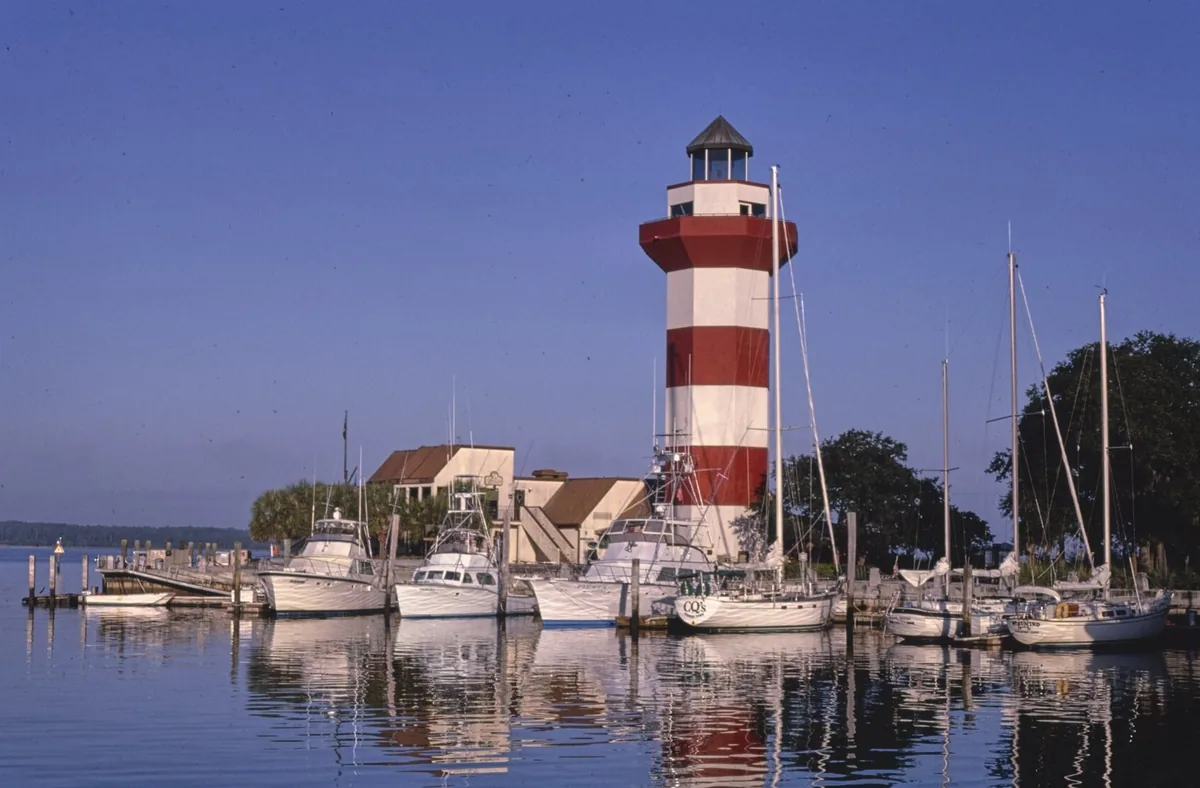 The red and white Harbour Town Lighthouse above boats moored in the marina at Hilton Head Island