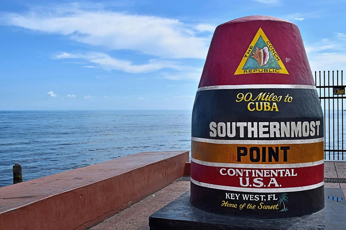 The striped Southernmost Point buoy in Key West, marked 90 miles to Cuba, beside the blue Florida Straits