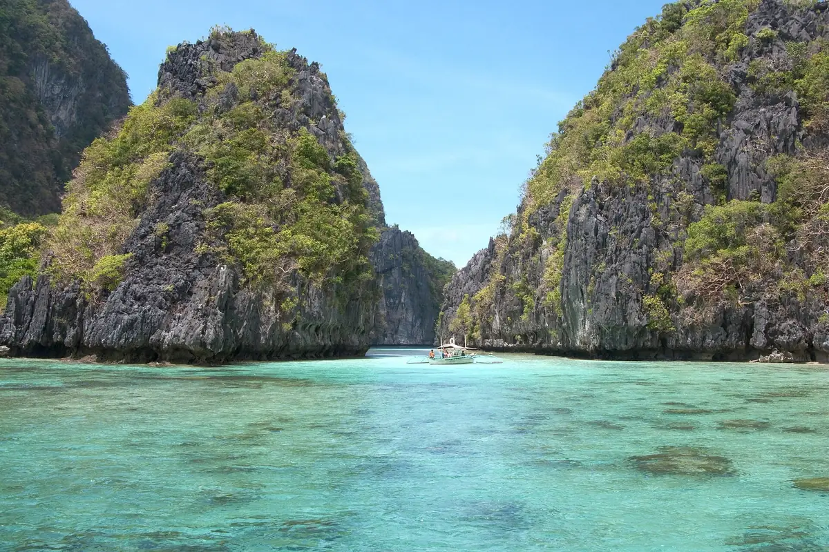 Limestone karst islands rising from the clear turquoise lagoon water of Bacuit Bay near El Nido, Palawan