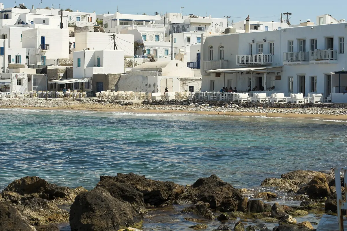 Whitewashed waterfront houses and tavernas above a rocky shore in the village of Naoussa on Paros