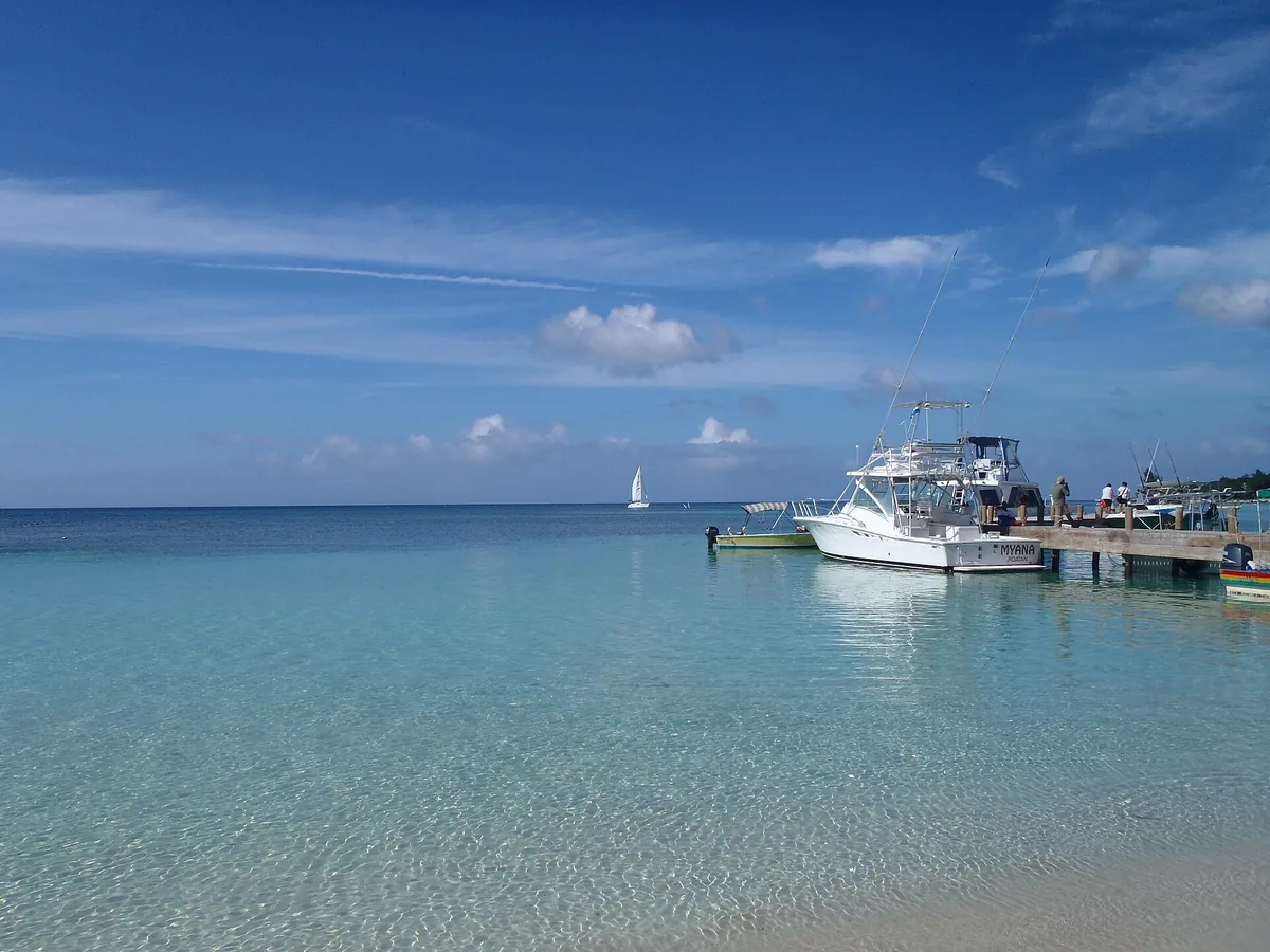 Clear shallow turquoise water at West Bay on Roatán, with fishing boats tied up at a wooden dock