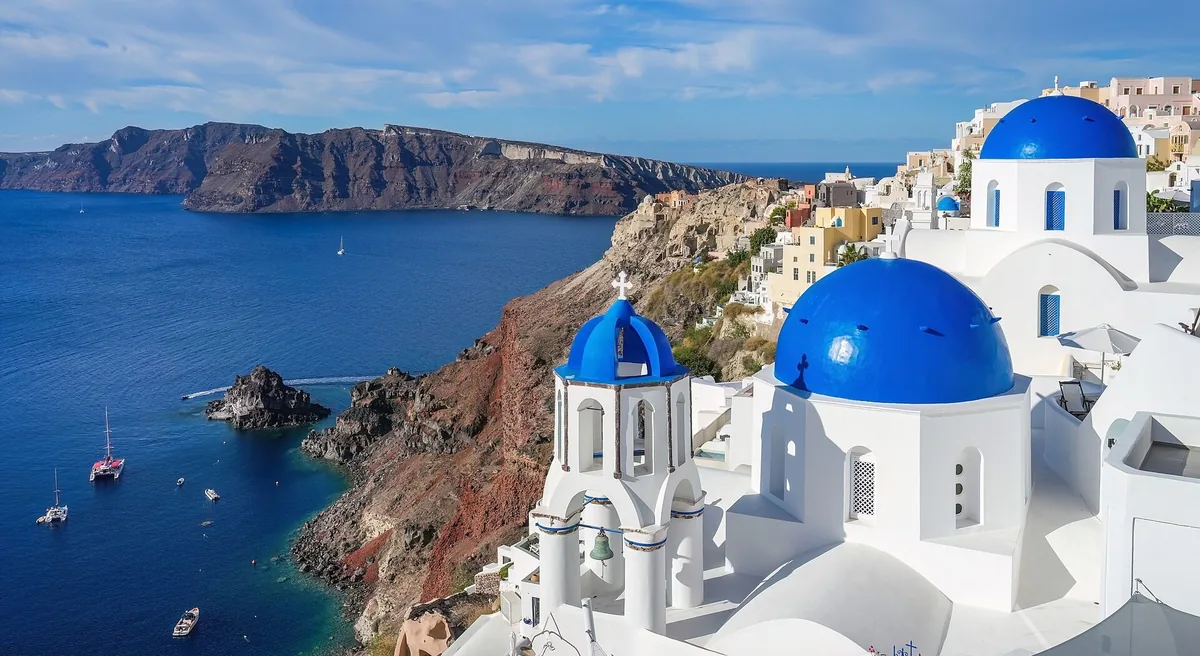 Blue-domed white churches of Oia above the caldera cliffs and deep blue sea of Santorini
