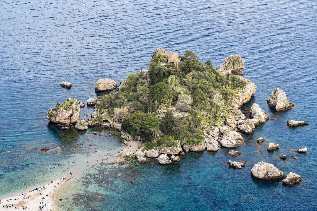 Aerial view of the rocky islet of Isola Bella and its sand bar in the clear water off Taormina, Sicily