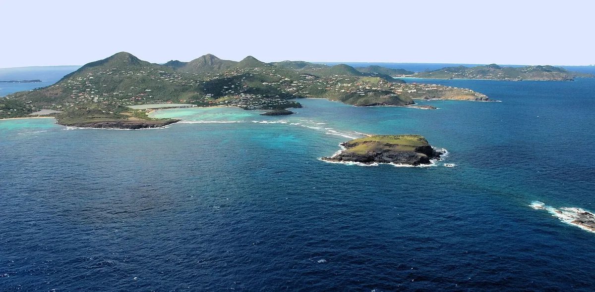 Aerial view of St. Barts, with green hills, turquoise bays and a rocky islet off the coast